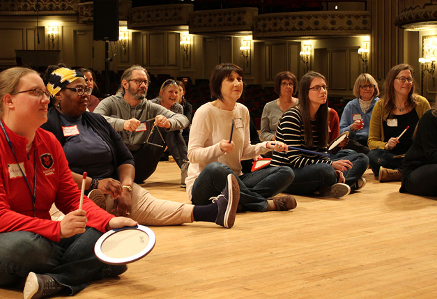 Teachers sitting on stage participating in education workshop