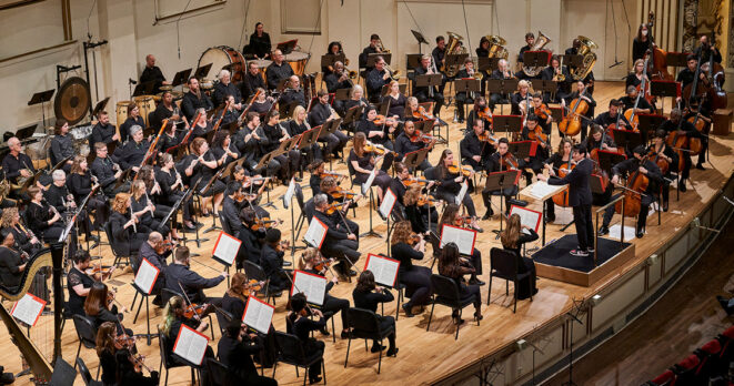 Wide shot of orchestra playing on stage