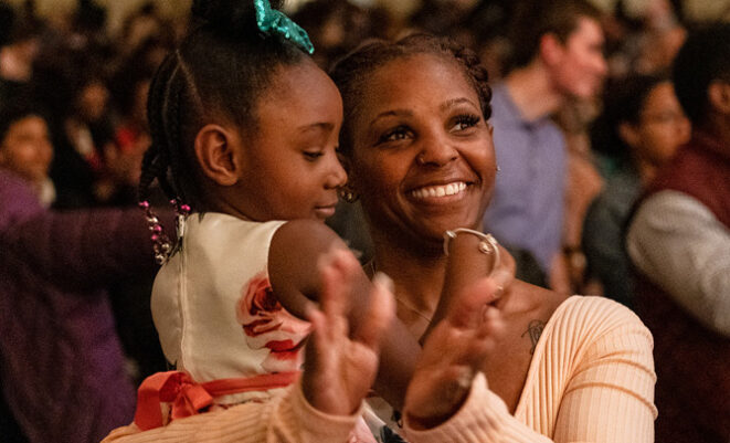 Woman clapping with child in her arms