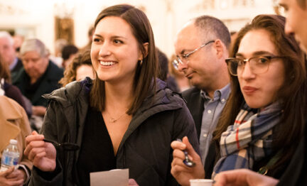 Young adults stand in group conversing in foyer