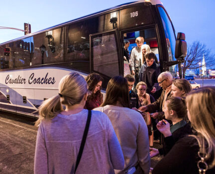 Group of people stand outside coach bus