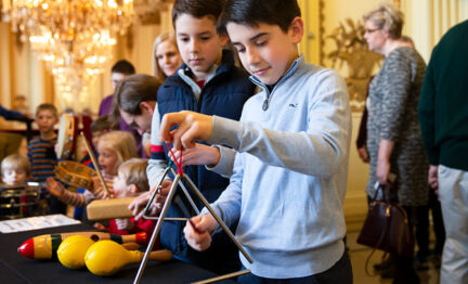 Two children playing the triangle as part of Instrument Playground