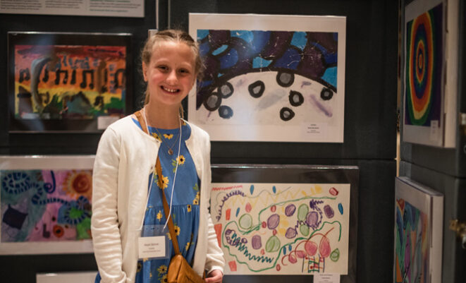 Young girl standing in front of artwork that is part of the Picture the Music program