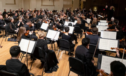 Orchestra members on stage with Stéphane Denève conducting