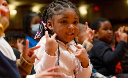 Child holding up two fingers as part of education concert participation