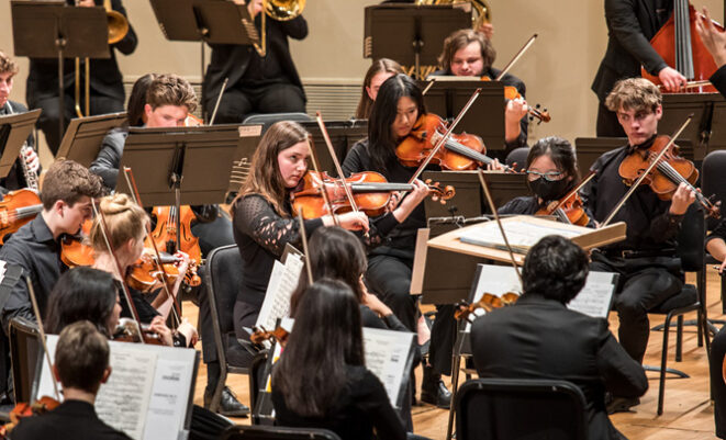 Youth Orchestra musicians playing string instruments on stage