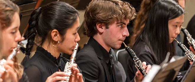 Youth Orchestra musicians play wind instruments on stage
