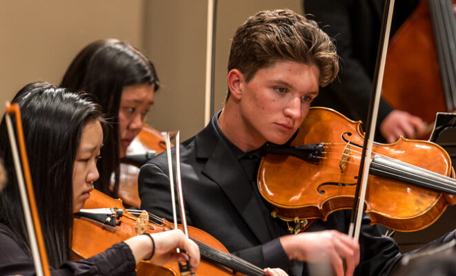 Youth Orchestra musicians play string instruments on stage