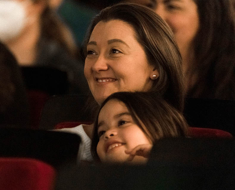 Mother and child smiling in auditorium seats