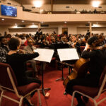 Quartet of string musicians play in front of audience sitting in church
