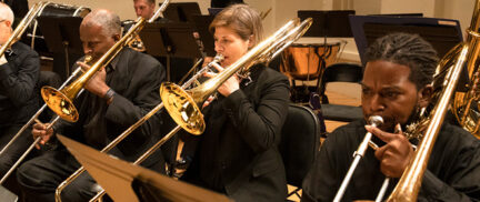 SLSO musician Amanda Stewart playing the trombone along with educators as part of Extra Credit program on stage