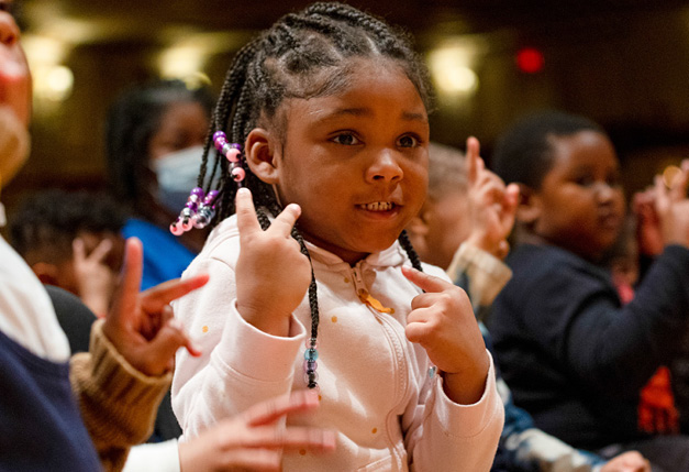 Child holding up two fingers as part of education concert participation