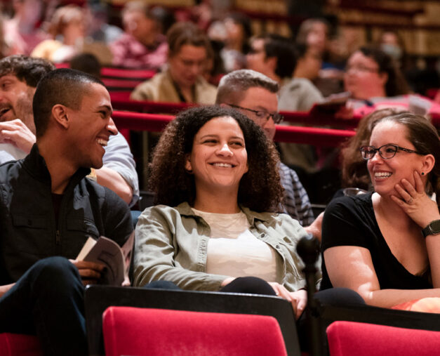 Audience members sitting and smiling in group conversation in auditoriums seats