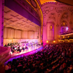 Wide shot of audiences watching musicians play on stage