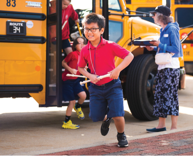 Child running off a school bus to an SLSO education concert