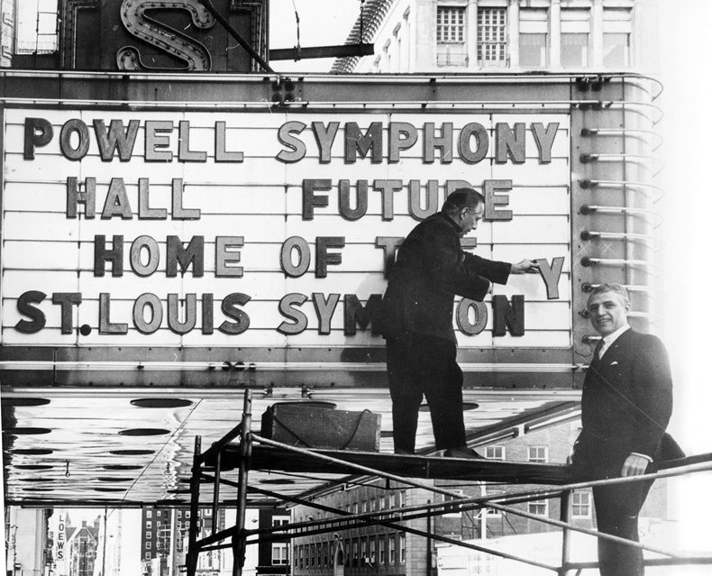 Black and white image of two men placing letters in marquee that say "Powell Symphony Hall Future Home of the St. Louis Symphony"