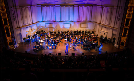 SLSO musicians playing on stage with guest artist during special presentation with blue and purple lighting effects
