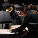 Timpanist Shannon Williams writing on a music sheet during rehearsal