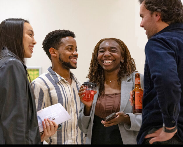 Four young adults conversing with drinks in a foyer