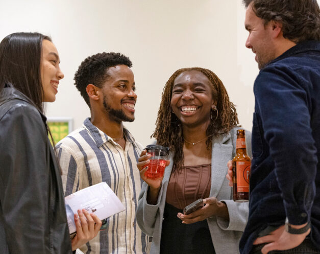 Four young adults conversing with drinks in a foyer