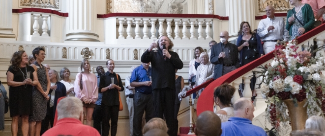 Stéphane Denève raising a glass during a toast with patrons in Powell Hall foyer